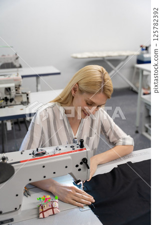 Pretty young female fashion designer working in her studio 125782392