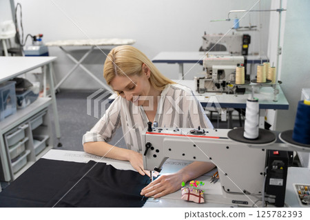 Pretty young female fashion designer working in her studio and smiling 125782393