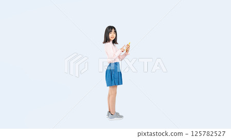 Full-body photo of a girl using a smartphone 125782527