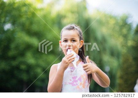 A pretty girl enjoying a delicious ice cream in the summer. Girl with ice cream on a walk in the park. A pretty girl enjoying a delicious ice cream in the summer. Girl with ice cream on a walk in the park. 125782917