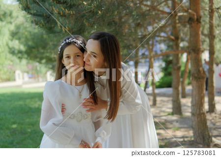 An exquisitely dressed young mother and her lovely daughter. Mom hugs her beautiful daughter. An exquisitely dressed young mother and her lovely daughter. Mom hugs her beautiful daughter. 125783081