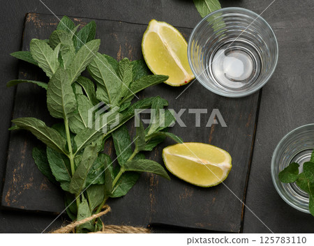Bunch of fresh green mint, lime slices, glasses, top view. Cocktail ingredient Bunch of fresh green mint, lime slices, glasses, top view. Cocktail ingredient 125783110