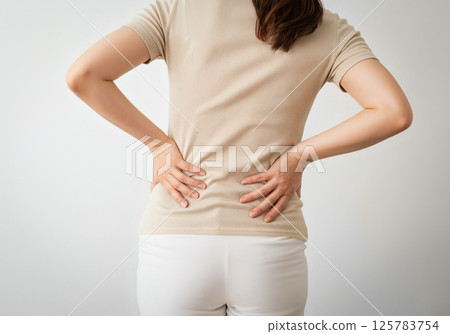 A woman with both hands on her hips enduring back pain 125783754