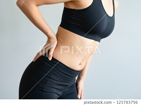 A woman leaning forward and holding her waist 125783756