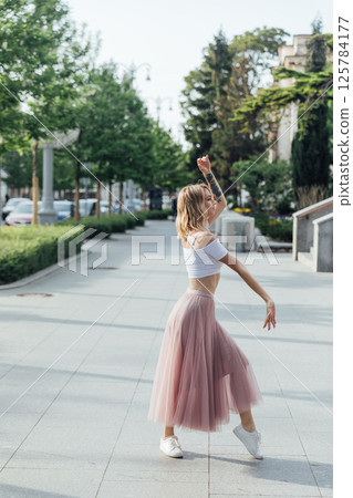 Blonde in dress dancing to music on street 125784177