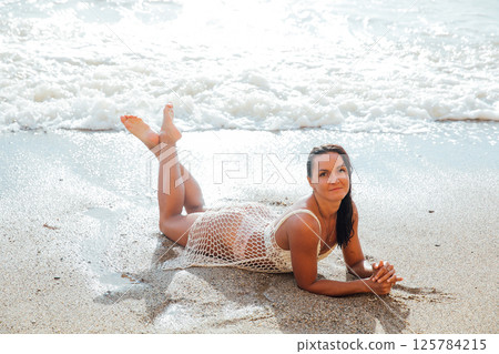 woman in a light swimsuit swims on a sandy sea beach woman in a light swimsuit swims on a sandy sea beach 125784215