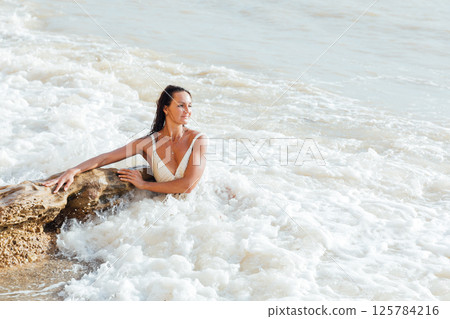 woman in a light swimsuit swims on a sandy sea beach woman in a light swimsuit swims on a sandy sea beach 125784216