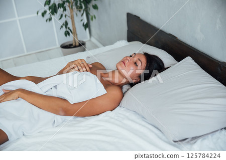 woman in light lingerie lying in the bedroom on the bed in the evening woman in light lingerie lying in the bedroom on the bed in the evening 125784224