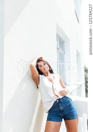 brunette woman in summer shorts standing on the balcony 125784227