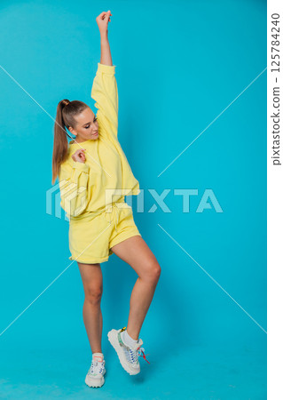 A woman in a yellow tracksuit raised her hand up 125784240