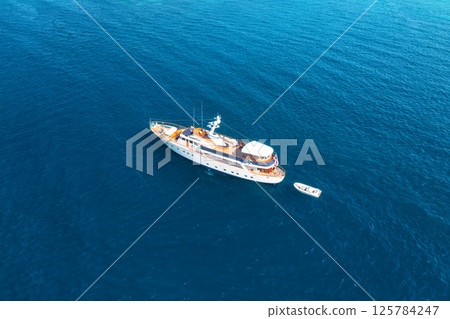 Aerial view of a luxurious yacht sailing on calm, deep blue ocean 125784247