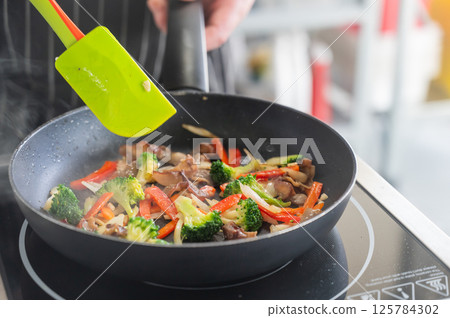 Beef and vegetables are fried in a frying pan.  125784302