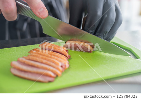 The chef slices the roast duck. The chef slices the roast duck. 125784322