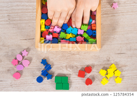 Preschooler playing thread and colorful beads used to making bracelets 125784354