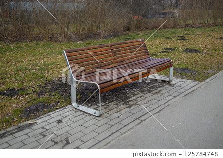 Park Bench on a Path in a Public Park with Trees in the Background 125784748