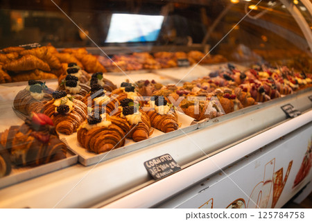 Display of fresh croissants and pastries in a bakery. 125784758