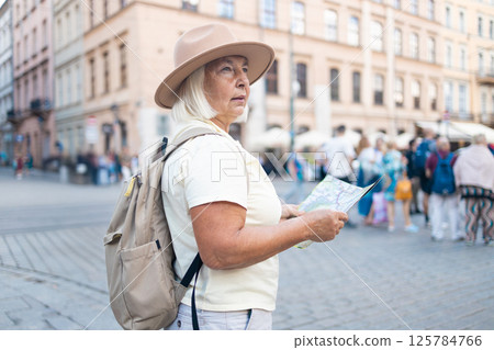 Senior woman exploring the city with a map, sightseeing in the square. 125784766