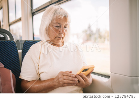 Senior woman using smartphone on a bus while traveling. 125784783