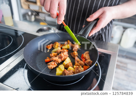 The chef fries pork in sweet and sour. The chef fries pork in sweet and sour. 125784839
