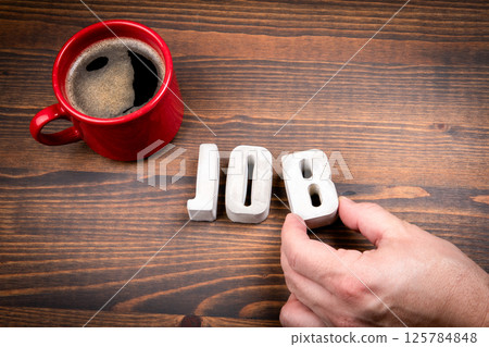 Job Concept. Concrete alphabet letters and coffee mug on dark wooden texture background 125784848
