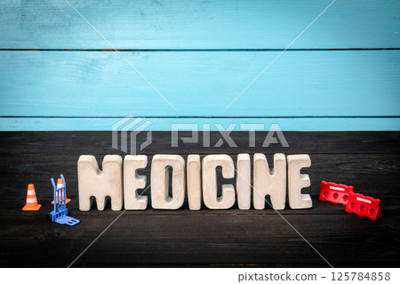 MEDICINE. Text from concrete alphabet letters on a black wooden table 125784858