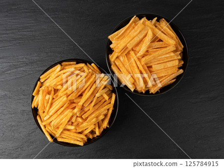 Fried chips sticks, finger potato chips, golden shoestring fries pile, French fries 125784915