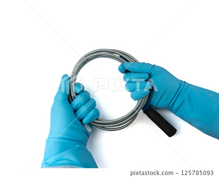Metal drain auger tool isolated, plumbing snake or cable in hands in blue glove on white background 125785093