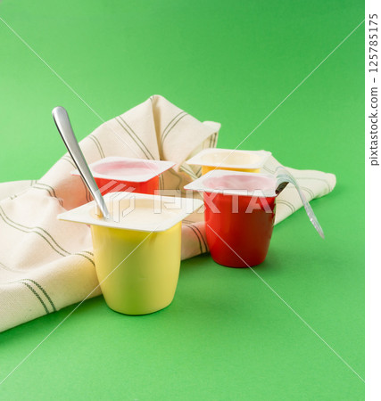 Yogurt cups set, pink and yellow fruit yoghurt in plastic pots, milk pudding container with spoon 125785175