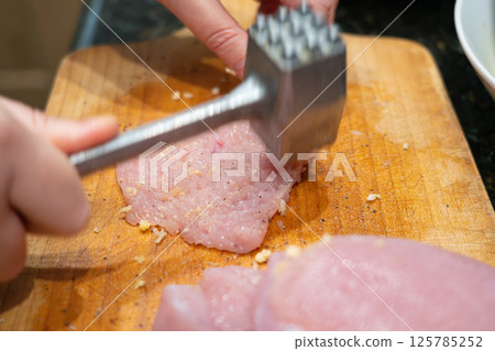 Tenderize meat, beating, hammering fillet pieces, cooking schnitzel process closeup 125785252