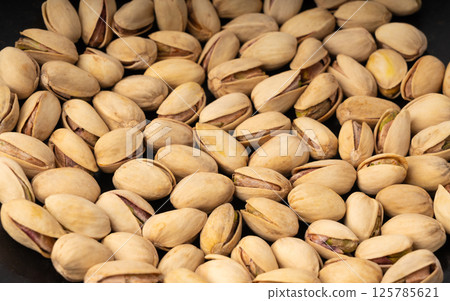 Fried salt pistachio nuts texture background. Baked pistachios pattern, roasted green pistache Fried salt pistachio nuts texture background. Baked pistachios pattern, roasted green pistache 125785621