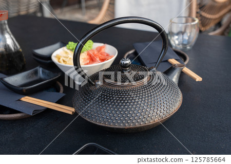 Japanese tea pot, black metal teapot, traditional iron kettle for tea drinking while waiting for sushi 125785664