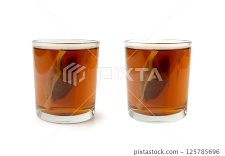 Herbal tea sachet in glass, hot water with chamomile and Hypericum or St. John's wort teabag Herbal tea sachet in glass, hot water with chamomile and Hypericum or St. John's wort teabag 125785696