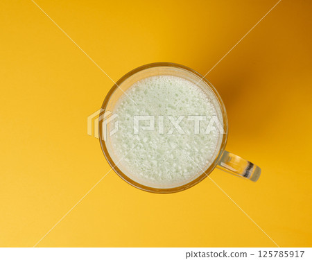 Vanilla milk shake in glass. Milkshake on yellow background, white whey protein smoothie Vanilla milk shake in glass. Milkshake on yellow background, white whey protein smoothie 125785917
