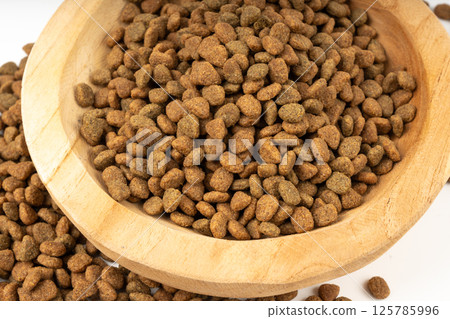 Dry pet food close up, dog kibble pile in wood bowl, puppy pellets macro, small canine protein 125785996