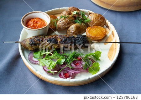 Georgian lula kebab plate. Bbq skewer, traditional barbecue dish with baked potatoes, sauce 125786168