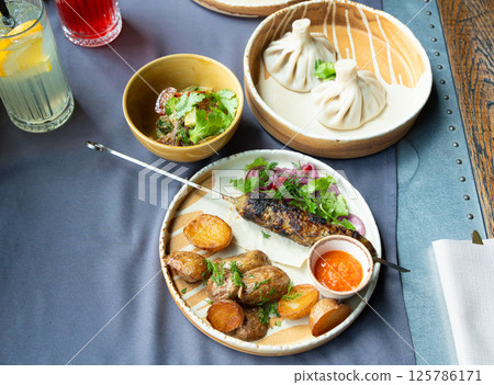 Georgian lula kebab plate. Bbq skewer, traditional barbecue dish with baked potatoes, sauce 125786171