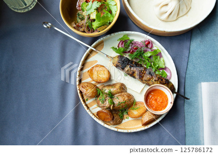 Georgian lula kebab plate. Bbq skewer, traditional barbecue dish with baked potatoes, sauce 125786172