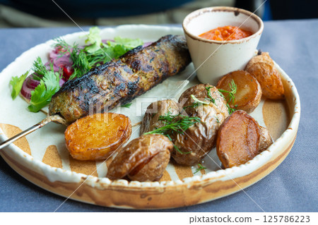 Georgian lula kebab plate. Bbq skewer, traditional barbecue dish with baked potatoes, sauce 125786223