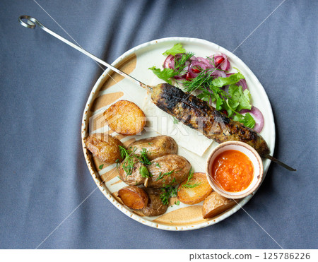 Georgian lula kebab plate. Bbq skewer, traditional barbecue dish with baked potatoes, sauce Georgian lula kebab plate. Bbq skewer, traditional barbecue dish with baked potatoes, sauce 125786226
