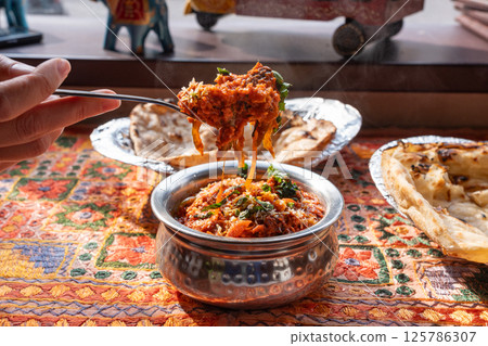 Lamb curry with tomatoes and fiery chili, traditional Indian Laal Maas served in a metal dish Lamb curry with tomatoes and fiery chili, traditional Indian Laal Maas served in a metal dish 125786307