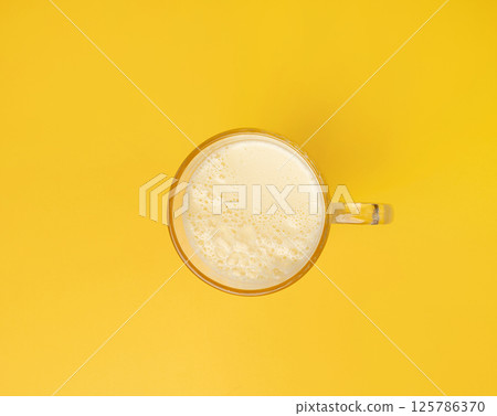 Vanilla milk shake in glass. Milkshake on yellow background, white whey protein smoothie Vanilla milk shake in glass. Milkshake on yellow background, white whey protein smoothie 125786370