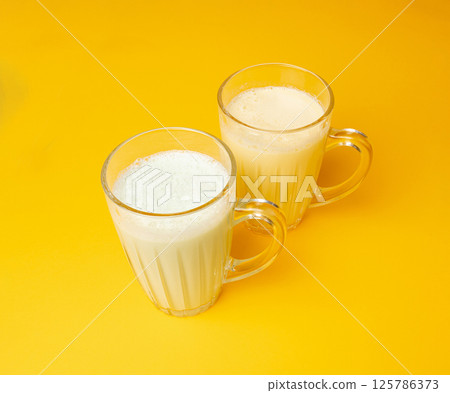 Vanilla milk shake in glass. Milkshake on yellow background, white whey protein smoothie Vanilla milk shake in glass. Milkshake on yellow background, white whey protein smoothie 125786373