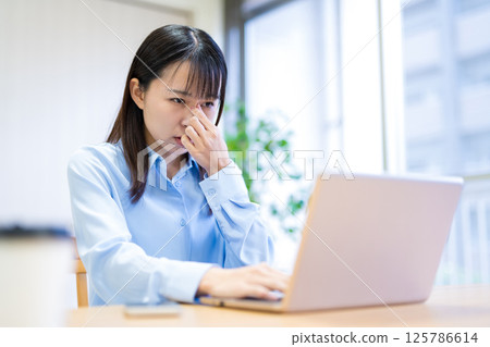 Young woman teleworking in the living room, eye strain, tired eyes, holding eyes, holding eye corners 125786614