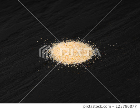 Garlic powder pile, dried granulated chopped crushed garlic cloves, cut into small pieces Garlic powder pile, dried granulated chopped crushed garlic cloves, cut into small pieces 125786877