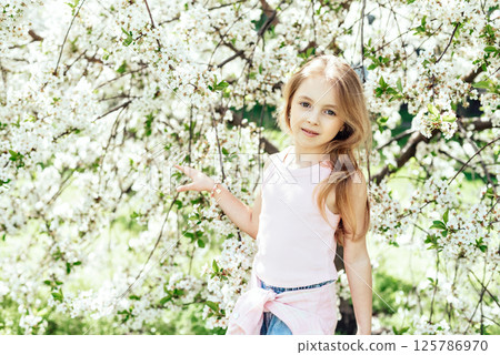 Serene Spring Portrait of Child Surrounded by Flowers by blooming white cherry blossoms symbolizing love, family connection, and joyful celebration of Mother's Day in spring. warm spring greetings 125786970