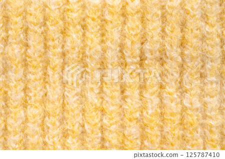 Knitted woolen fabric pattern in pale yellow. Macro texture of a sweater 125787410