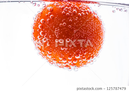 Ripe tomato in the glass create a feeling of immersion and purity. The surface vegetable is covered with numerous air bubbles. Ripe tomato in the glass create a feeling of immersion and purity. The surface vegetable is covered with numerous air bubbles. 125787479