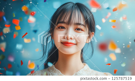 Portrait of charming young asian woman surrounded by colorful confetti on blue background 125787519