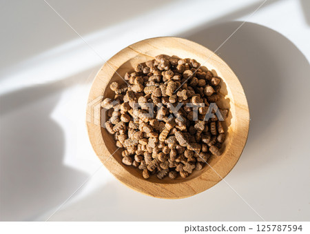 Dry pet food in sunlight, dog kibble pile, scattered puppy pellets, small canine protein croquette Dry pet food in sunlight, dog kibble pile, scattered puppy pellets, small canine protein croquette 125787594