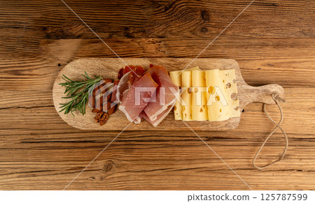 Cheese plate with prosciutto, jamon cut, parma ham, serrano slices, cured iberico closeup, cheese board 125787599